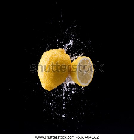 lemon and half lemon in water splash on black background