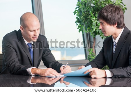 Relaxed businessman signing documents Royalty-Free Stock Photo #606424106