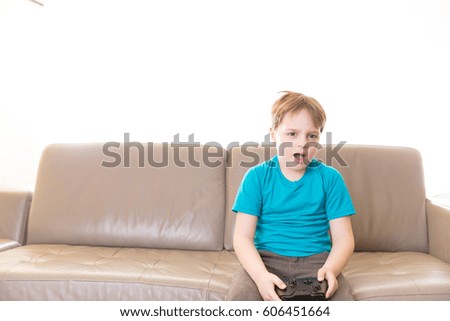 Little boy playing some video games at home using a controller, making different expressions.