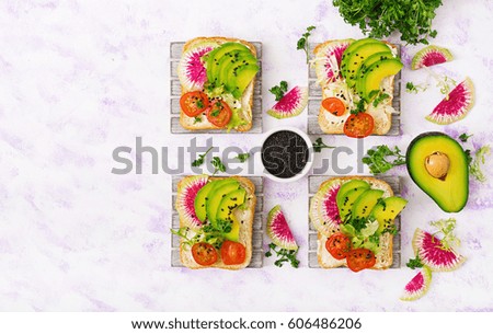 Vegan sandwiches with avocado, watermelon radish and tomatoes on a white background. Flat lay. Top view
