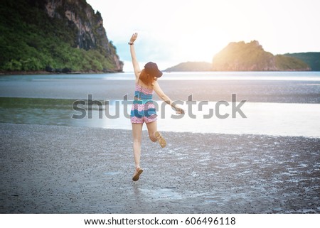 asian woman jumping on the beach with sunlight