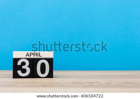 April 30th. Day 30 of month, calendar on wooden table and blue background. Spring time, empty space for text