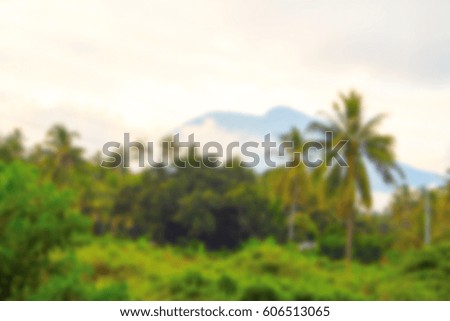 Abstract blur background with natural landscape. Tropical forest and mountain under sunny sky. Tropical island travel blurred image. Exotic holiday banner template. Palm trees and tropic greenery blur