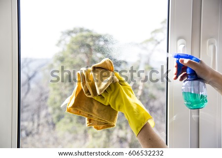 Window cleaning. Female hands in yellow gloves. With a bullet and a yellow rag