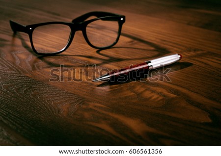 Glasses and pen on a wooden natural table. Office. Concept of work in a office and accessories. 