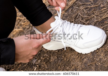 
Girl laces her shoelaces on sneakers