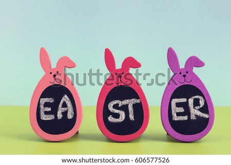 Written word Easter on three Bunny Eggs on blue and green colored background. Greeting card concept, negative space