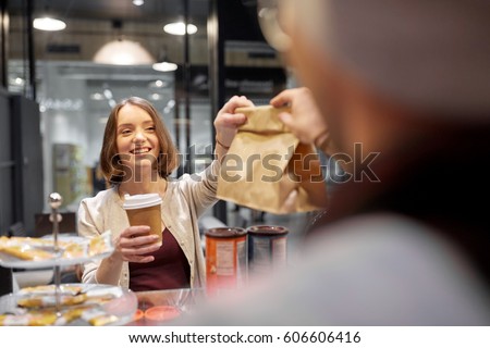 small business, takeaway food, people and service concept - happy female customer with coffee cup taking paper bag from man or barman at vegan cafe Royalty-Free Stock Photo #606606416