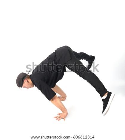 Young muscular man stands on his hands. He is wearing black clothes and snapback . white background