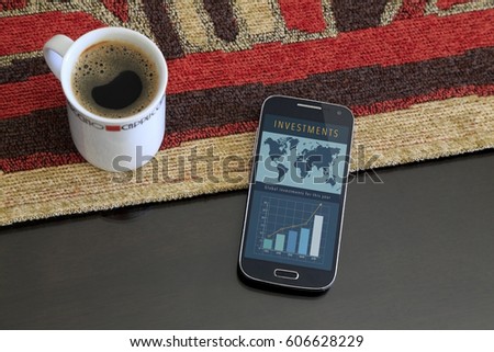 Smartphone with a investment web page on the screen. Beside a cup of coffee. Marketing, app, web page, app.