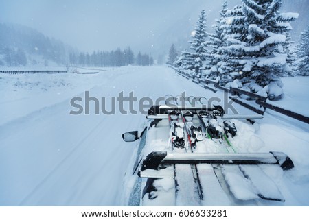 Ski trip with skis on the car roof during snowfall