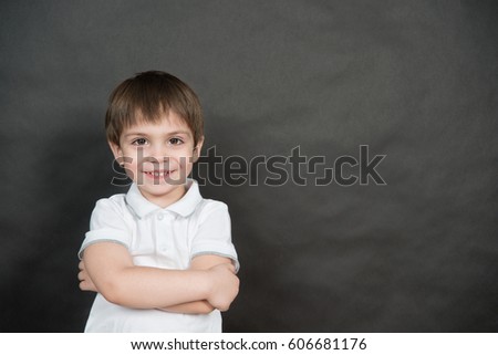 Portrait of the little boy in the white polo shirt standing in front of the blackboard.