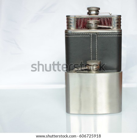 Three flat flask for alcohol on a glass table