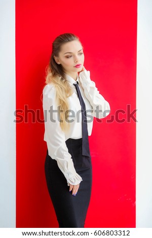 Attractive young woman, office worker, dressed in a white shirt and black skirt, with documents in the office