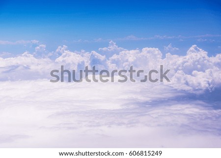 White clouds against blue sky view through an airplane window for a background.