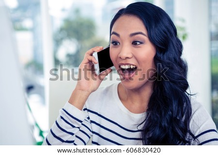 Surprised Asian woman on phone call in office