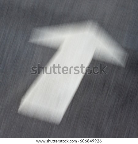 close up of motion blur white arrow on asphalt black road