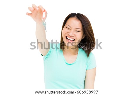Young woman holding a key and smiling on white background
