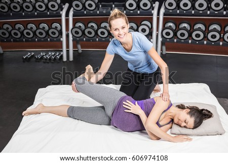 Pregnant woman stretching with her trainer at the gym