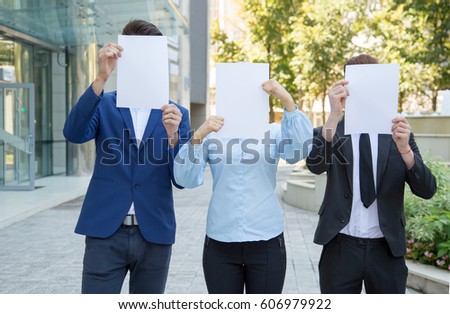 Three business people holding a blank sheet of paper covering their face. A group of people with clean sheets instead of face.