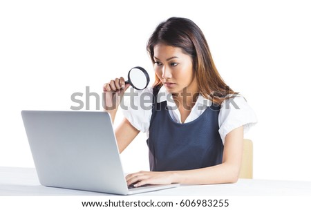 Businesswoman looking through magnifying glass and using laptop on white background
