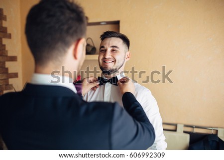 The groomsman helping to wear a butterfly for groom
