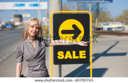 Woman standing outdoors near a banner with inscription sale