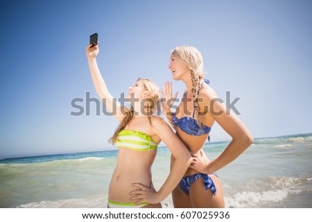Two friends in bikini taking a selfie at beach