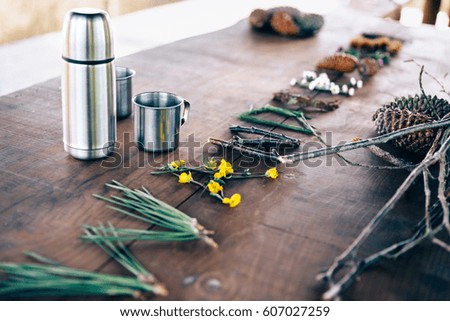 Table with thermos, cups and forest objects
