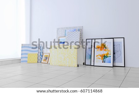 Set of modern paintings on floor at white wall