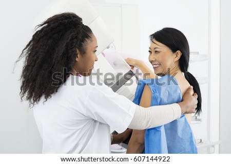 Happy Woman Looking At Doctor While Undergoing Mammogram X-ray T Royalty-Free Stock Photo #607144922