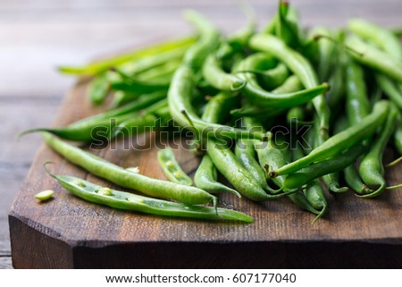 Green beans on wooden cutting board. Go green concept. Royalty-Free Stock Photo #607177040