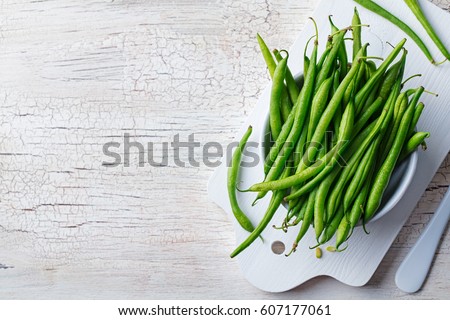 Green beans in white bowl on cutting board. Top view. Copy space. Royalty-Free Stock Photo #607177061