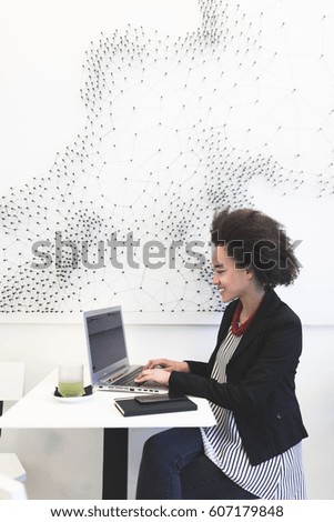 Confident cute Afro american business woman sitting in modern cafe and using her laptop or tablet.