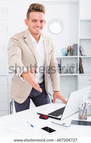 Business partner welcoming somebody at desk in office