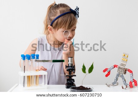 Little girl is behind the desk. Microscope and the tree are near her. Little robot. E-learning. Stem education. Royalty-Free Stock Photo #607230710