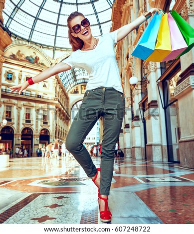 Discover most unexpected trends in Milan. Full length portrait of happy fashion monger in eyeglasses with colorful shopping bags having fun time in Galleria Vittorio Emanuele II