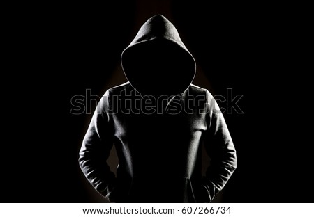 Mysterious man wit hoodie in silhouette isolated on black background Royalty-Free Stock Photo #607266734
