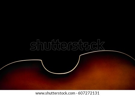 Back of sunburst bass guitar on bottom of image on black background