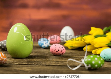 Colorful Easter eggs and tulips on wooden background