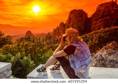 A travel photographer takes pictures of the spectacular monasteries of Meteora at sunset. Meteora is an area of Central Greece with several monasteries built on top of natural sandstone rock pillars.