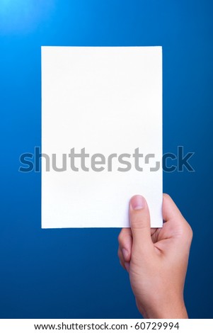 hand holding white greeting paper card on blue background