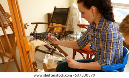 Female artist draws a pencil sketch drawing on canvas easel in art studio. Student girl learning to draw and paint.