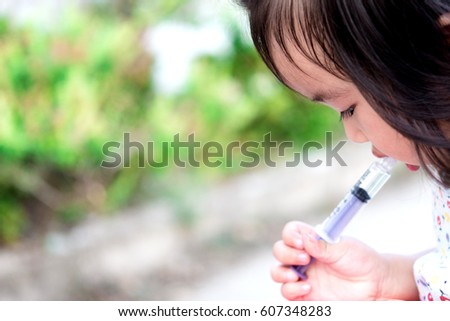 Child little girl gets medicine with a syringe in her mouth.