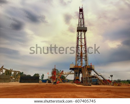 Oil and gas drilling rig onshore dessert with dramatic cloudscape Royalty-Free Stock Photo #607405745