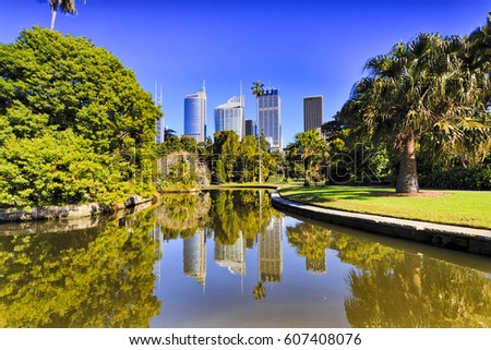 Sydney city Royal Botanic garden pond reflecting CBD skyscrapers surrounded by green exotic trees Royalty-Free Stock Photo #607408076