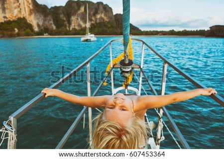 Vintage style child portrait. Happy baby girl on board of sailing yacht have fun discovering islands in tropical sea on summer coastal cruise. Travel adventure, yachting with kids on family vacation. Royalty-Free Stock Photo #607453364