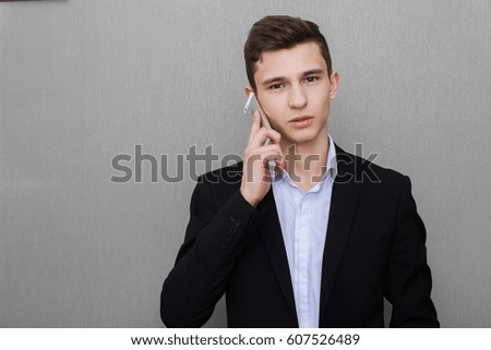 Closeup portrait, handsome young business man, happy guy, in vest, using cell phone, smiling, having a pleasant conversation, isolated gray black background. Human emotions, expression
