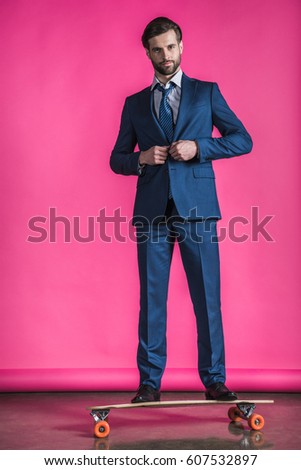 man in suit standing on skateboard on pink