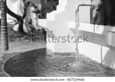 Decorative waterfall in the form of a faucet in sunny day - black and white